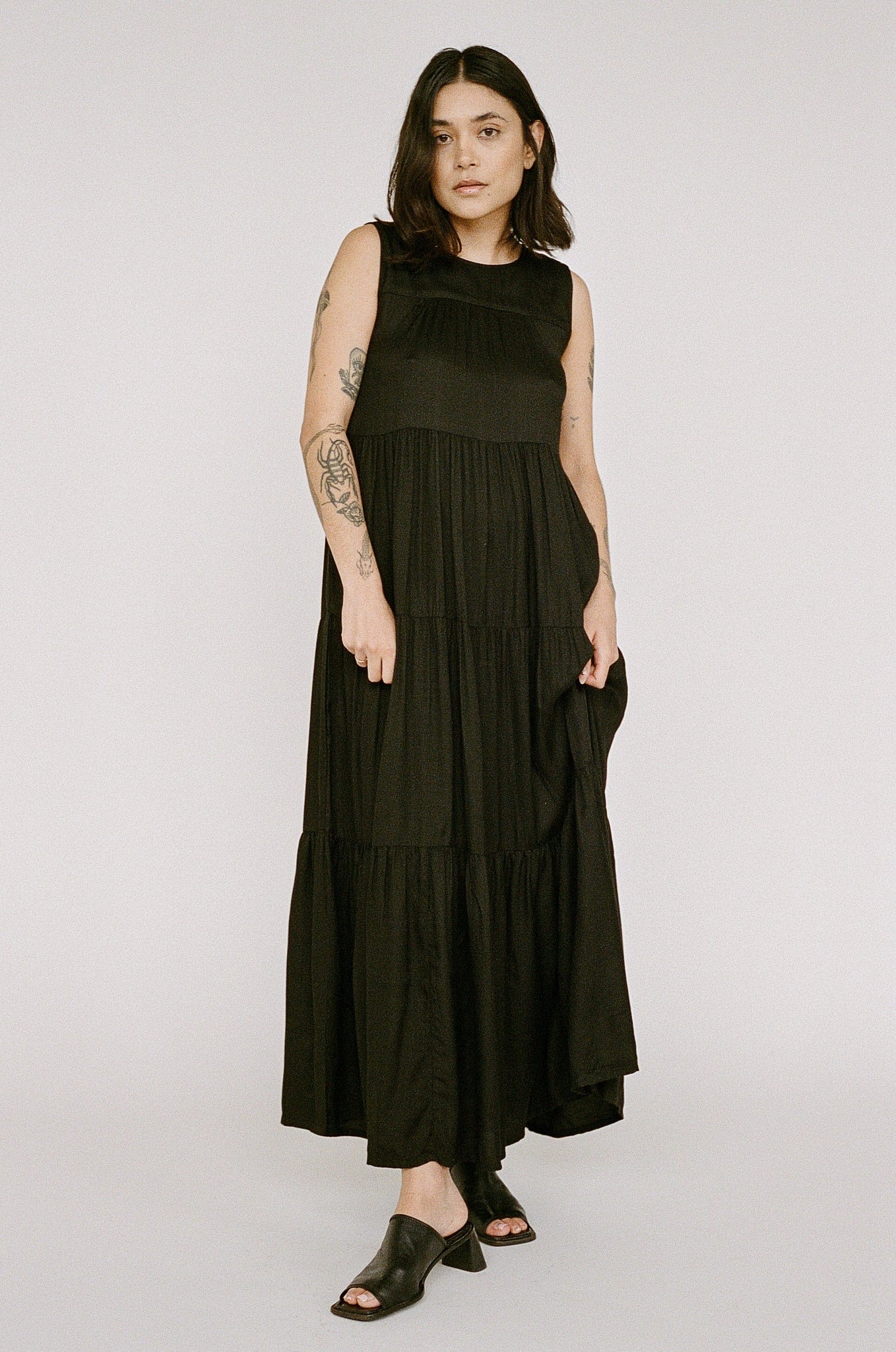 Woman in a Tiered Maxi Dress - Black handmade in India, standing against a neutral background.