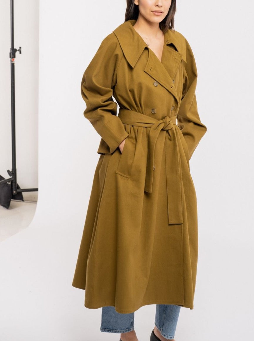 The model is wearing a Marin Trench - Olive with a storm flap.
