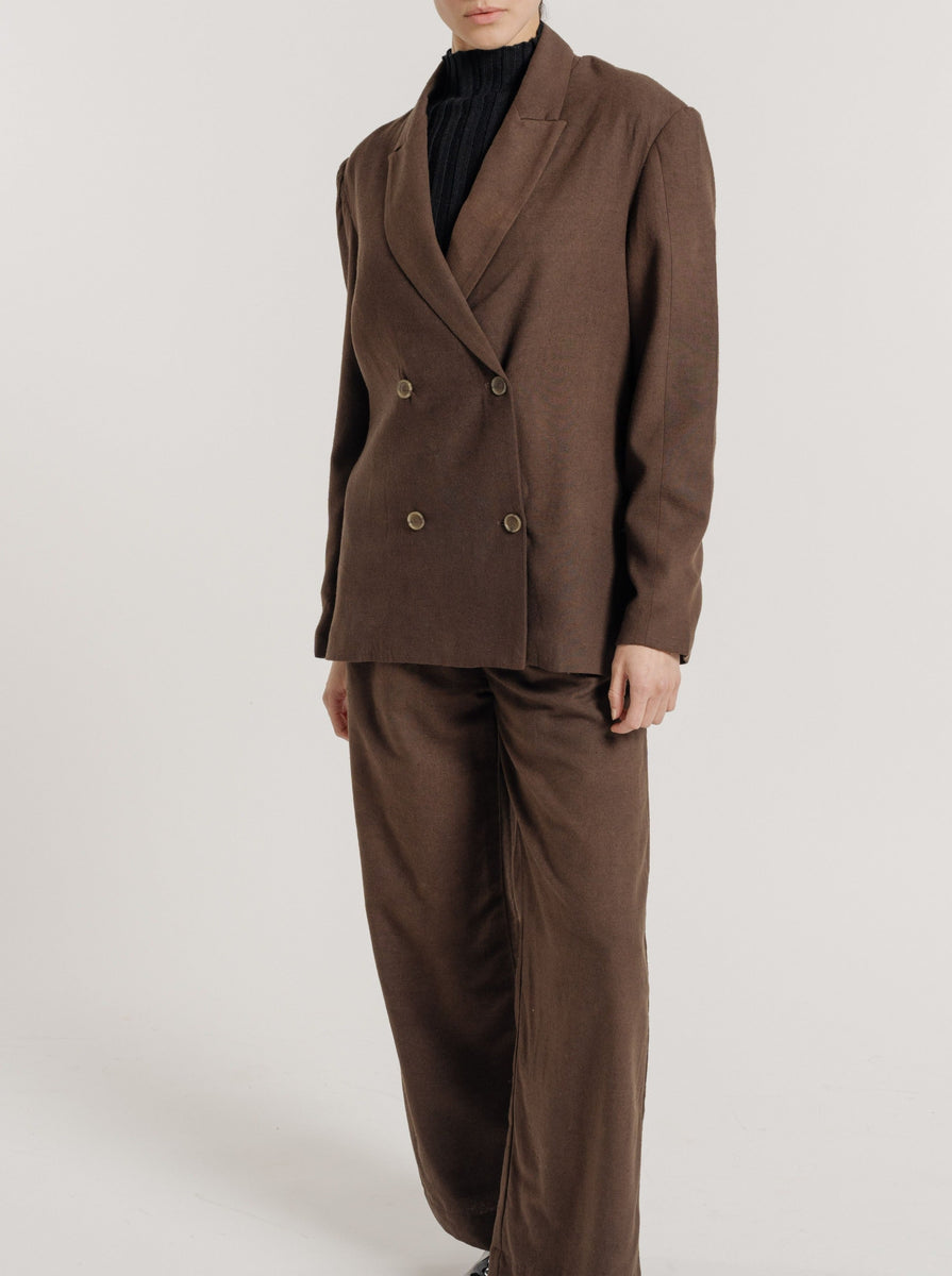 The model is wearing a Bea Blazer - Basalt Brown with a tailored waist.