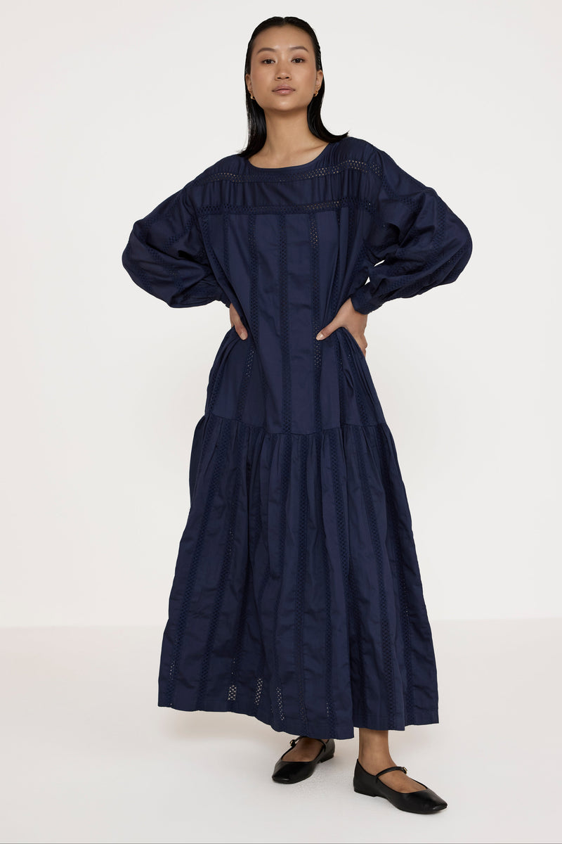 Woman wearing a long navy dress against a white background