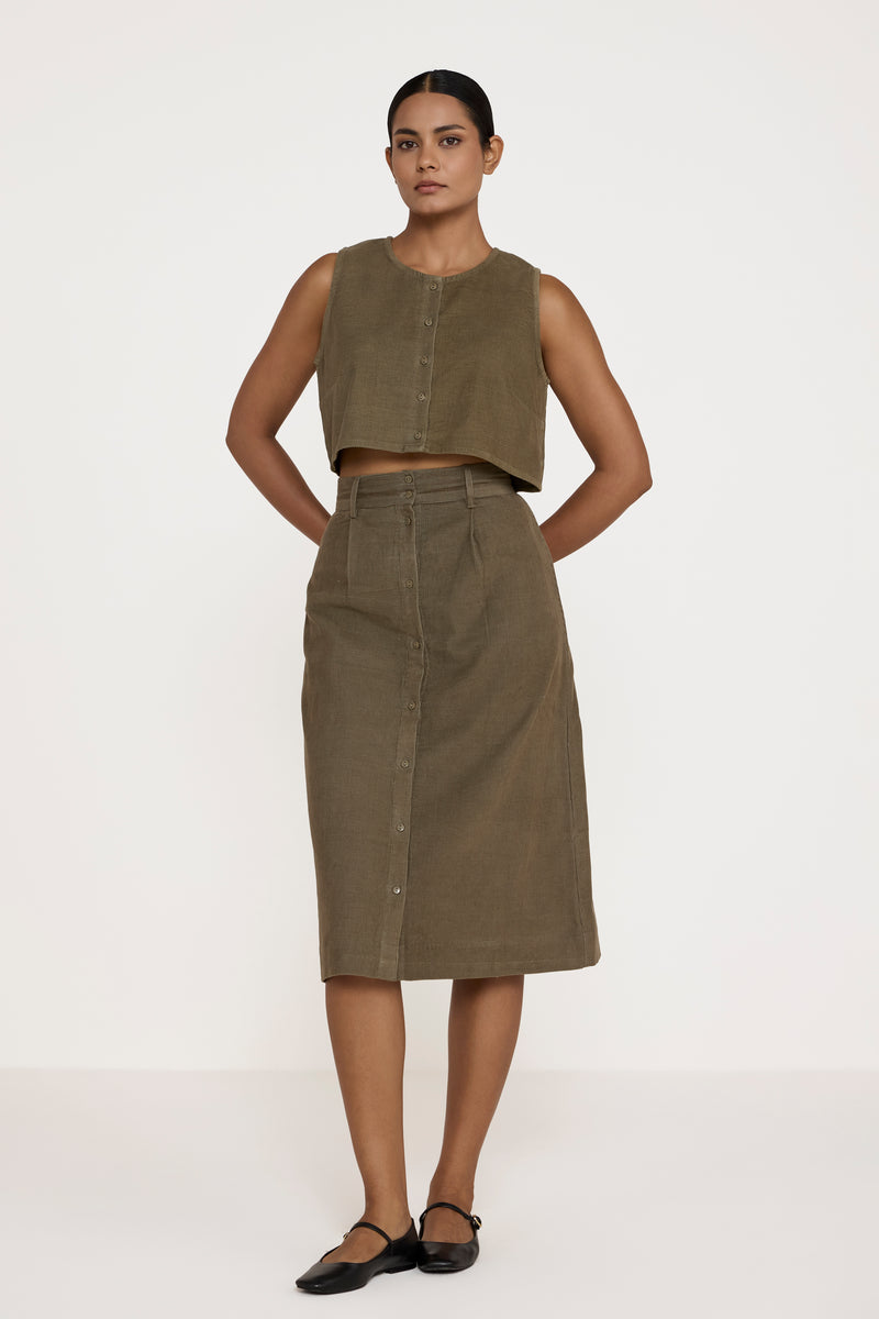 Woman wearing a green sleeveless top and skirt on a white background