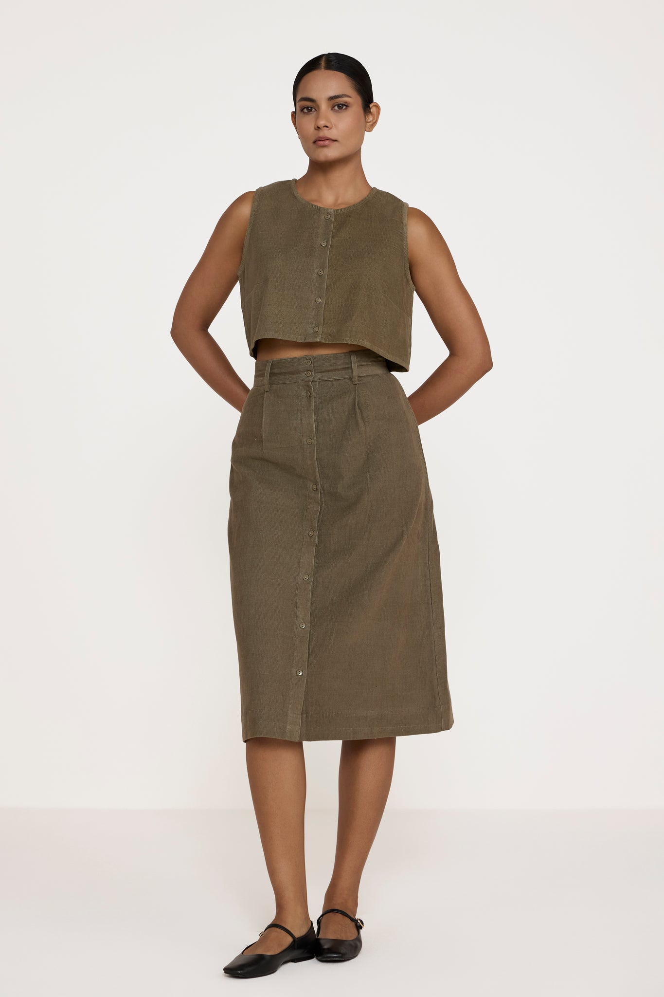 Woman wearing a green sleeveless top and skirt on a white background