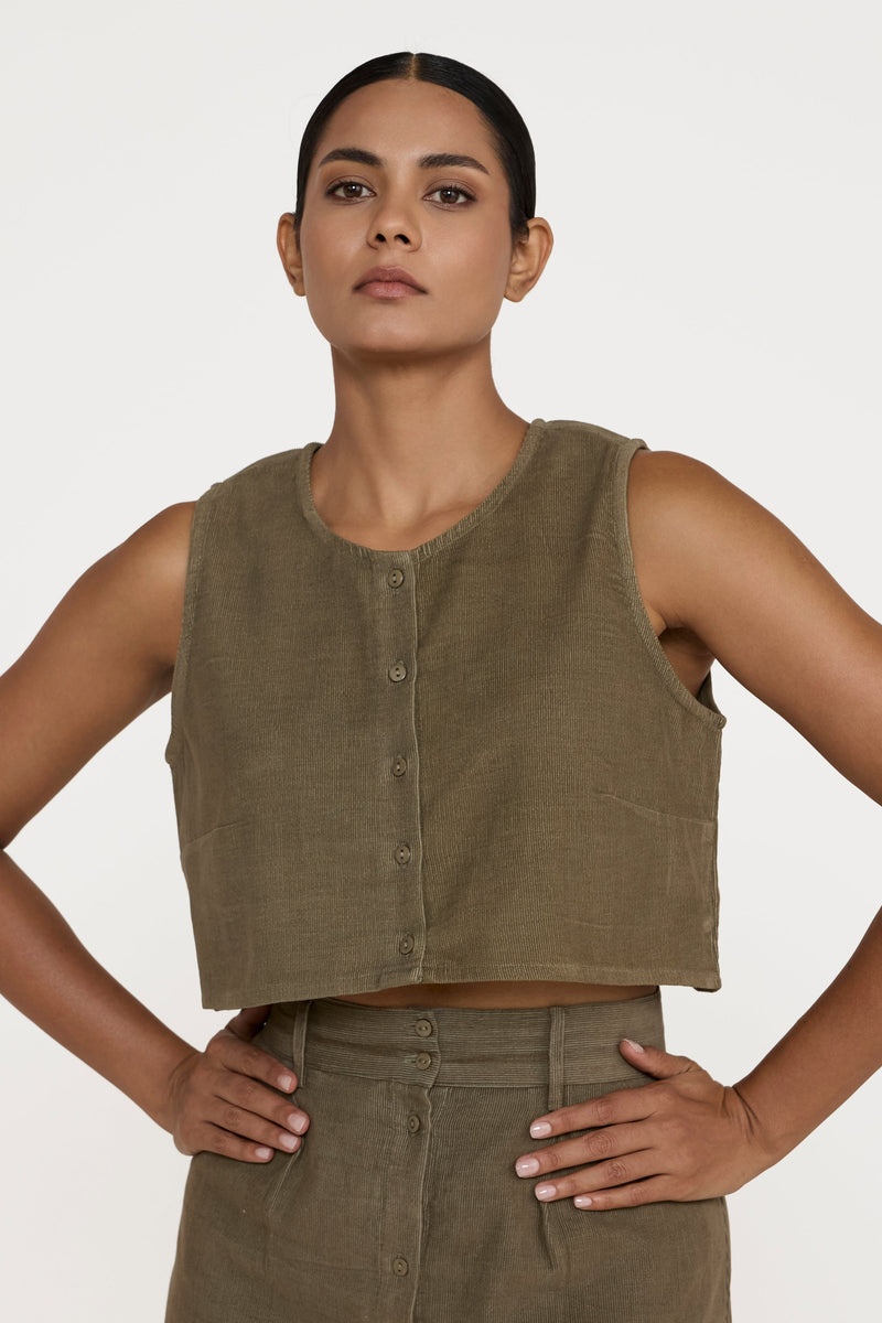 Woman wearing a green sleeveless top and skirt against a white background