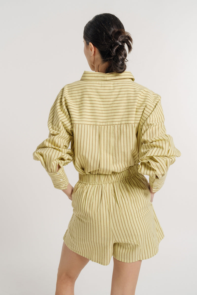 This SEO-optimized Easy Short - Feather Grass Stripe - Sample description provides a brief but detailed overview of a woman's back view, showcasing her in a stylish yellow striped romper.