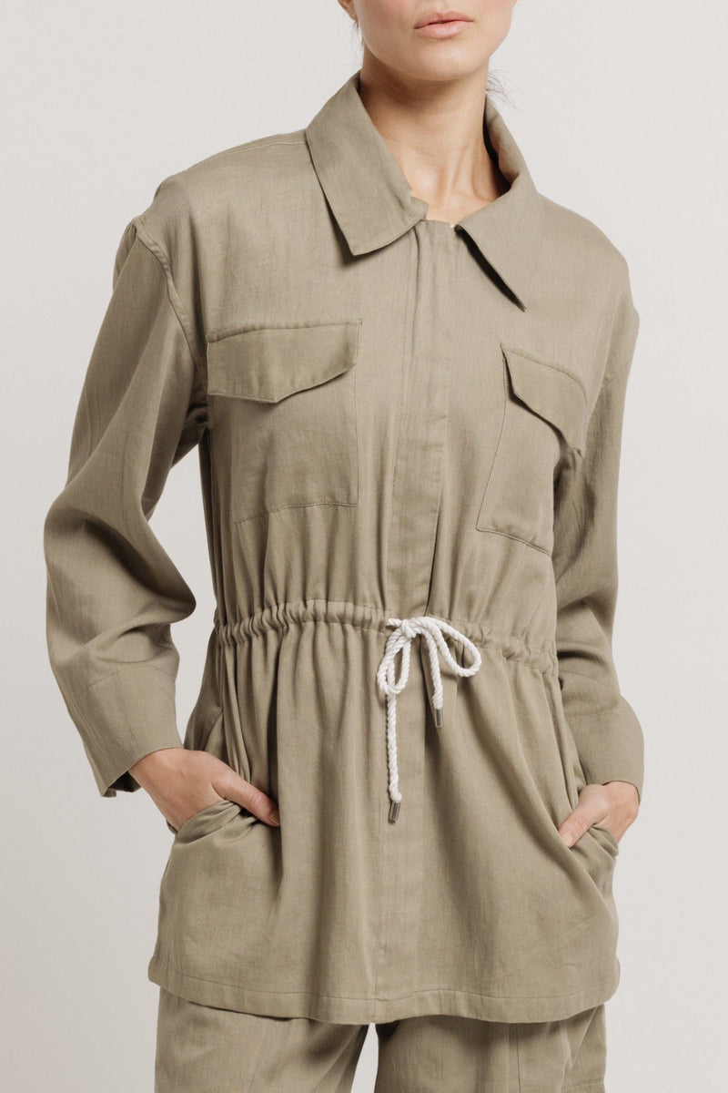 The model is wearing a lightweight Drawstring Utility Jacket - Putty and pants.