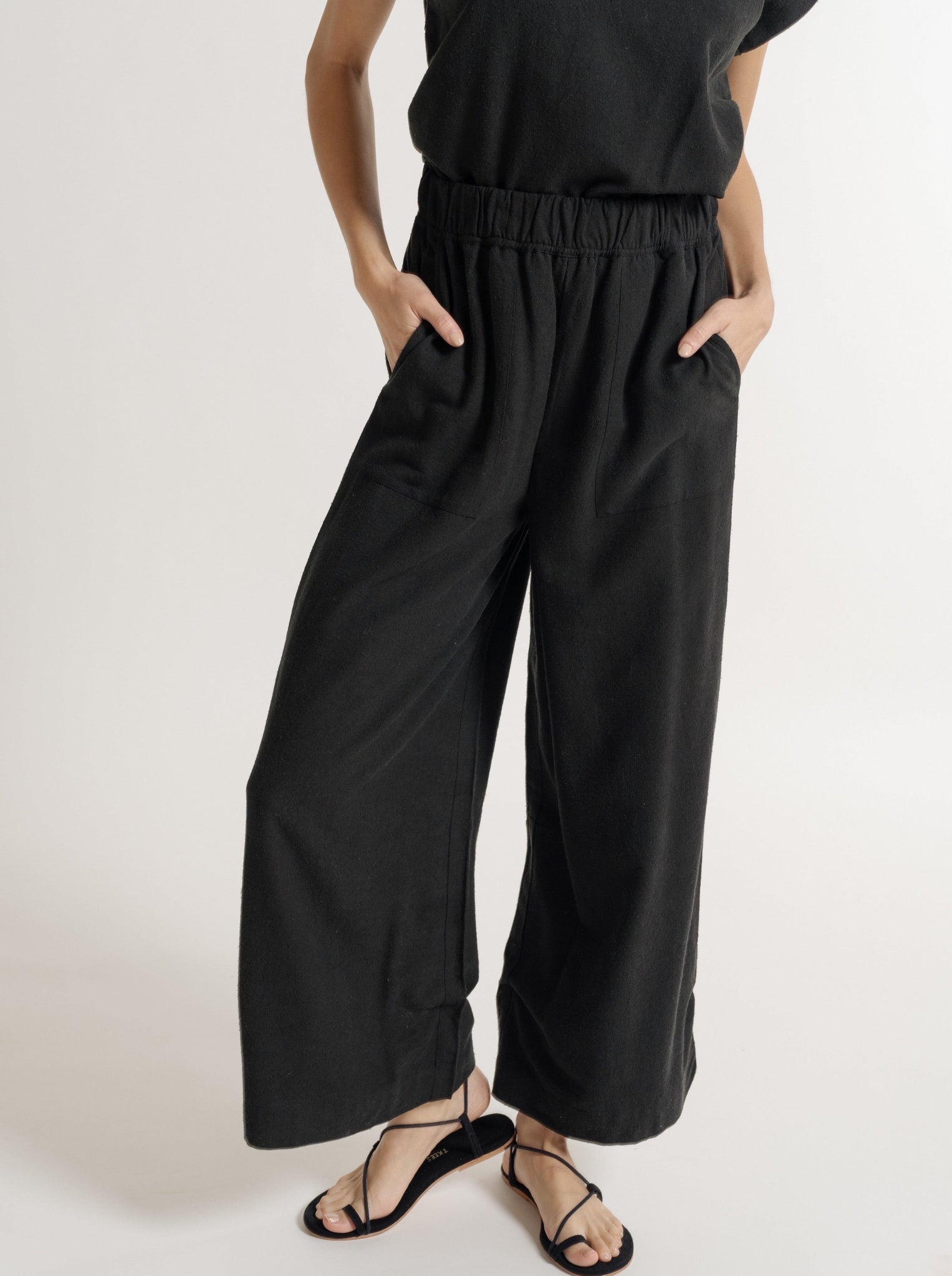 An eco-conscious woman wearing an Everyday Pant - Black Silk Noil - Pre-order jumpsuit.