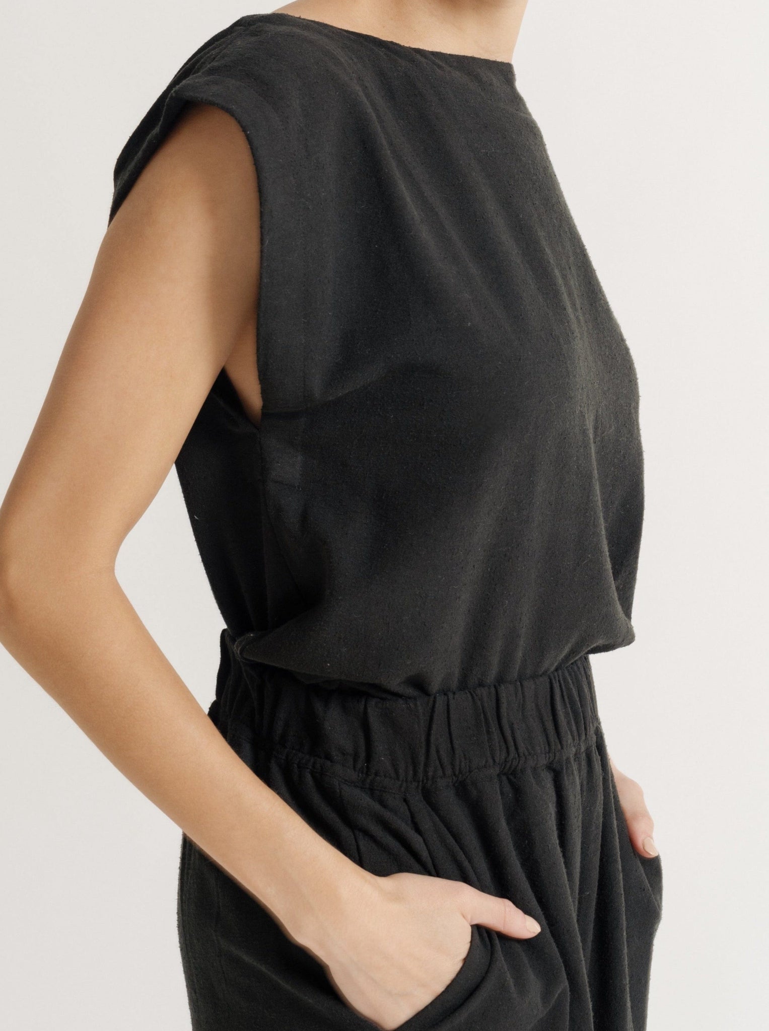 The model is wearing a sustainable Everyday Top - Black Silk Noil jumpsuit with pockets, crafted from textured silk noil.
