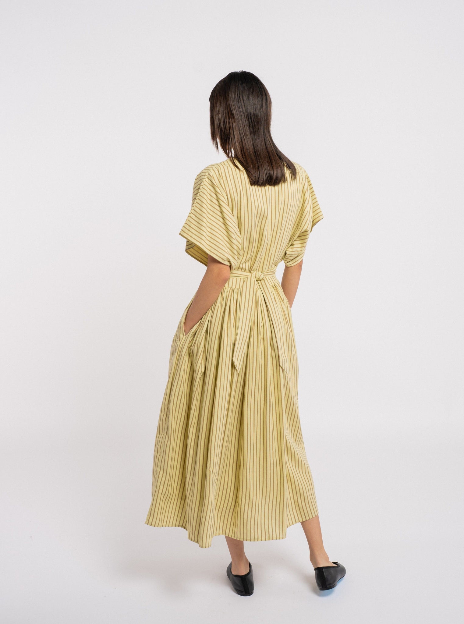 The back view of a woman wearing the Anita Dress - Feather Grass Stripe.