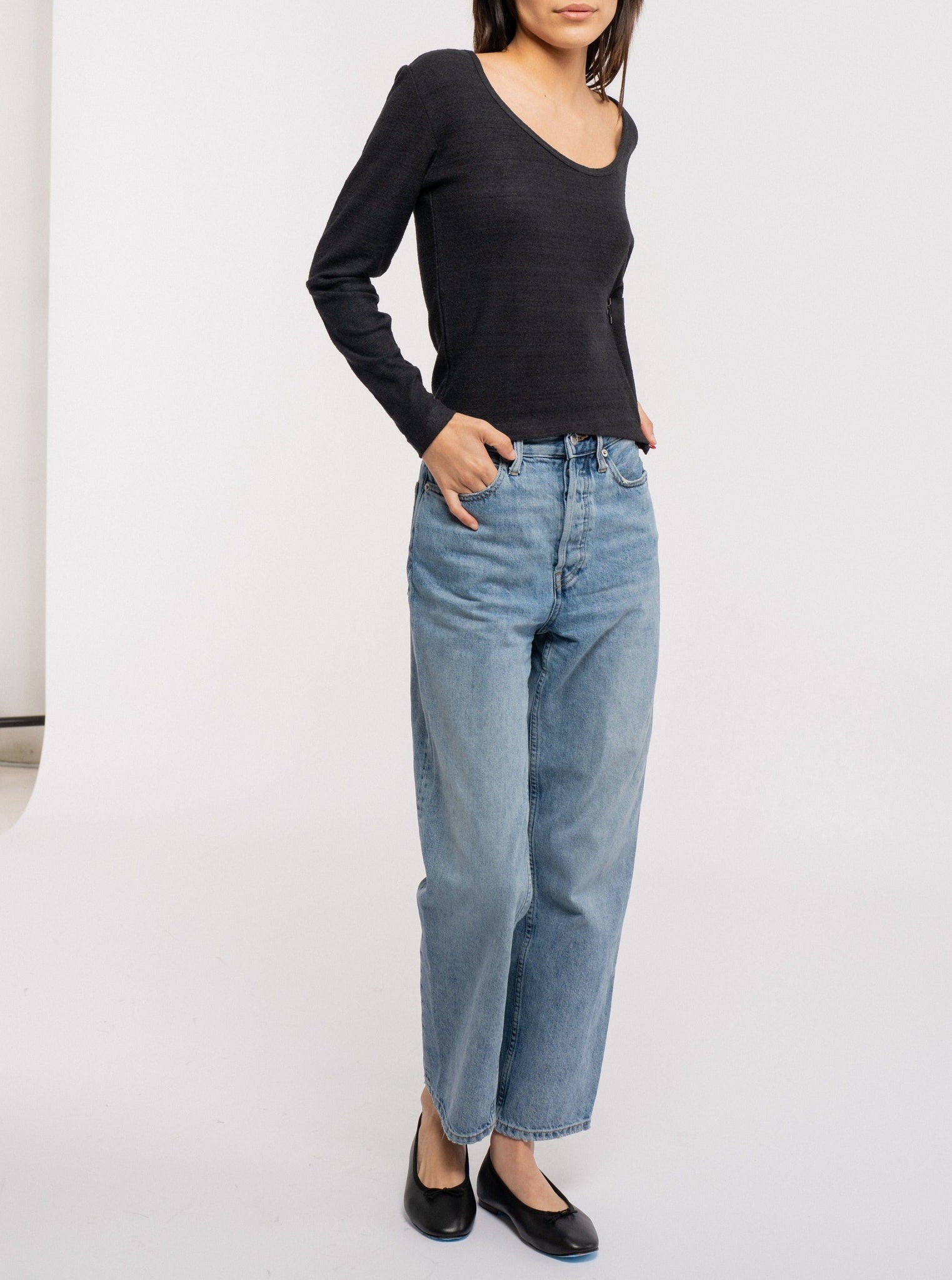 The model is wearing a black silk noil Scoop Neck Tee - Black and jeans.