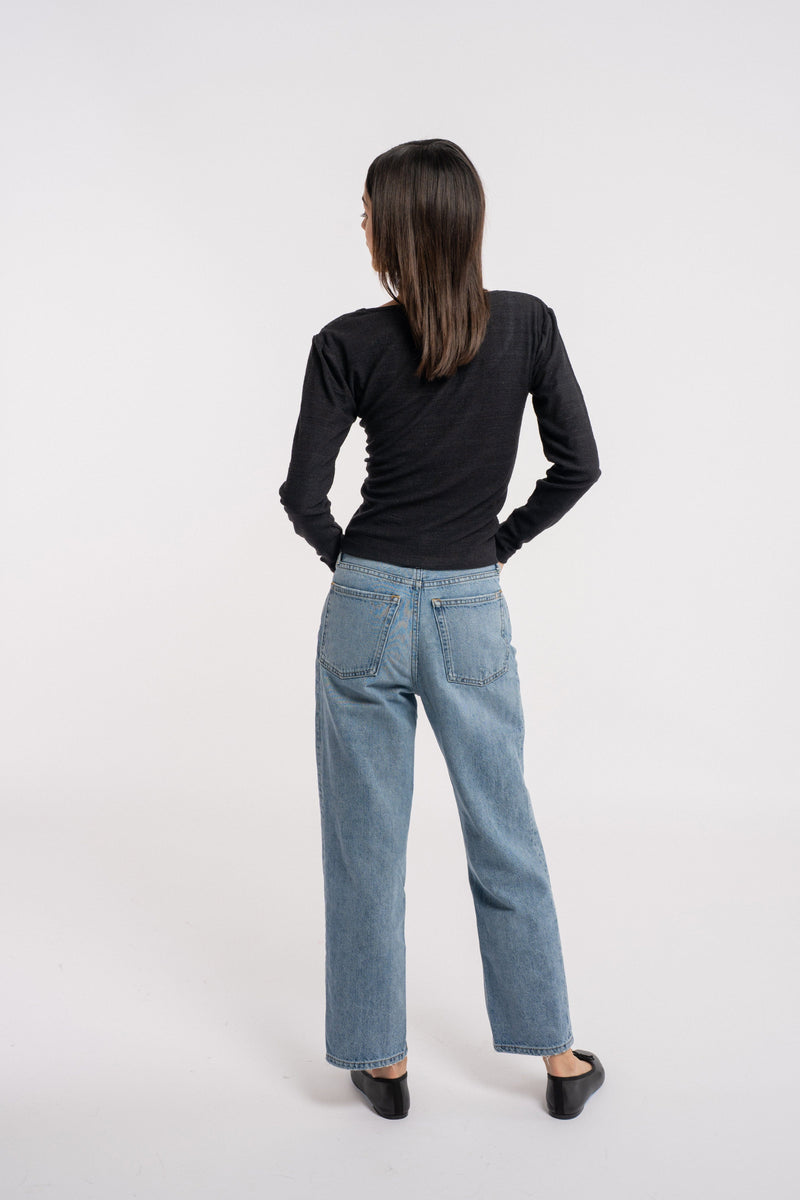 The back view of a woman wearing jeans and a Ballet Scoop Tee - Black - pre-order sweater.