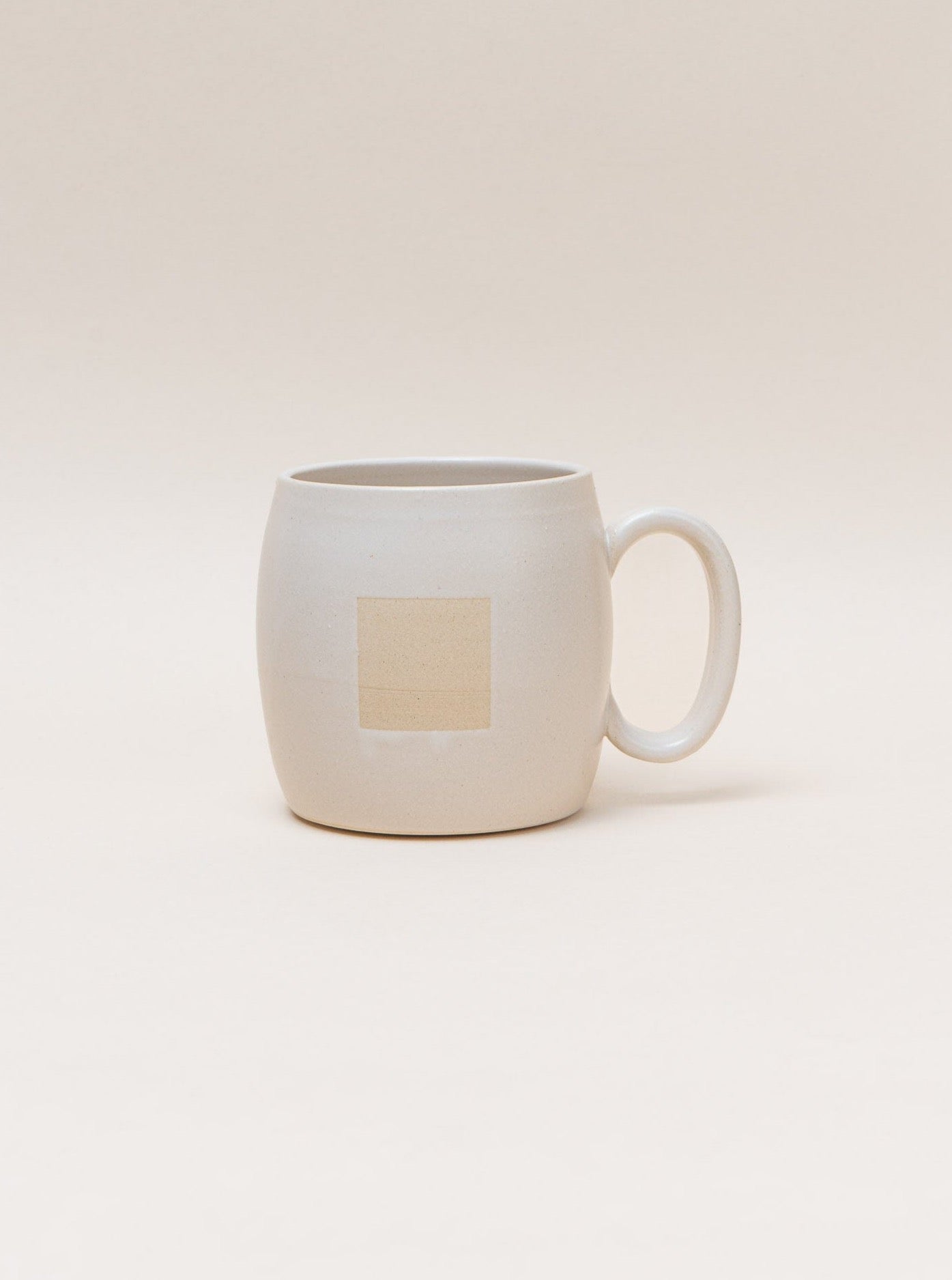 A Negative Space Mug - Cream handmade by a ceramic artist, featuring a square design.