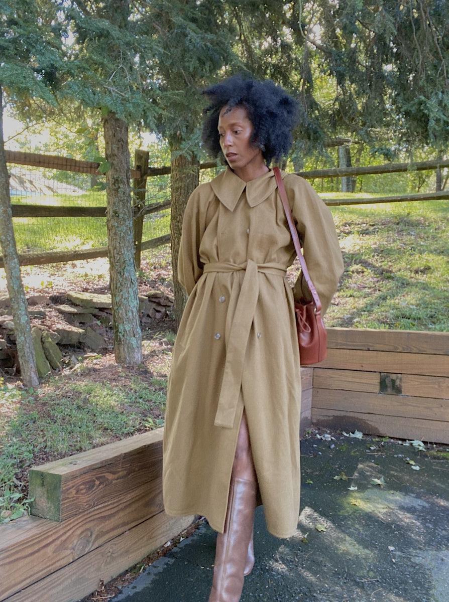 A woman wearing a handmade Marin Trench Coat - Olive and boots.