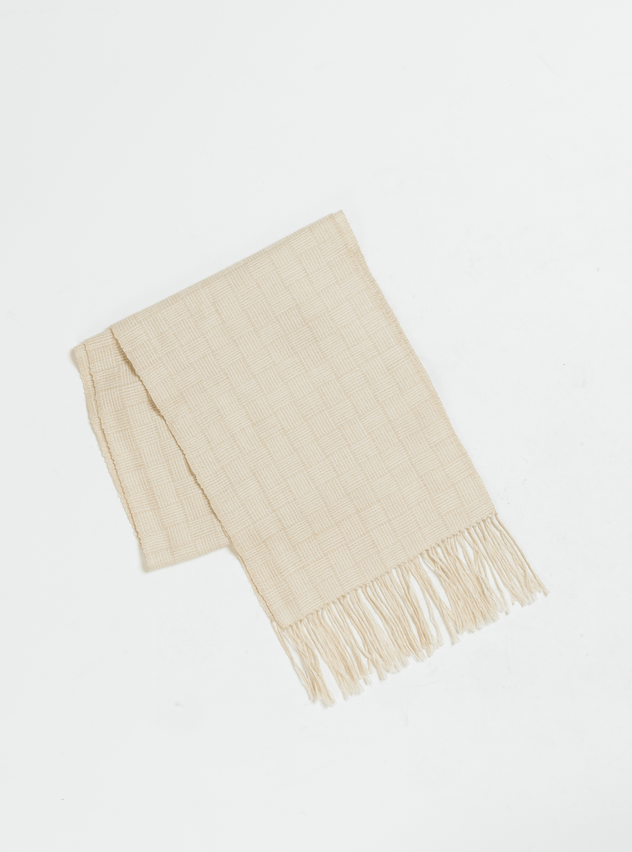 A lightweight beige woven fringed scarf - Oat on a white background.