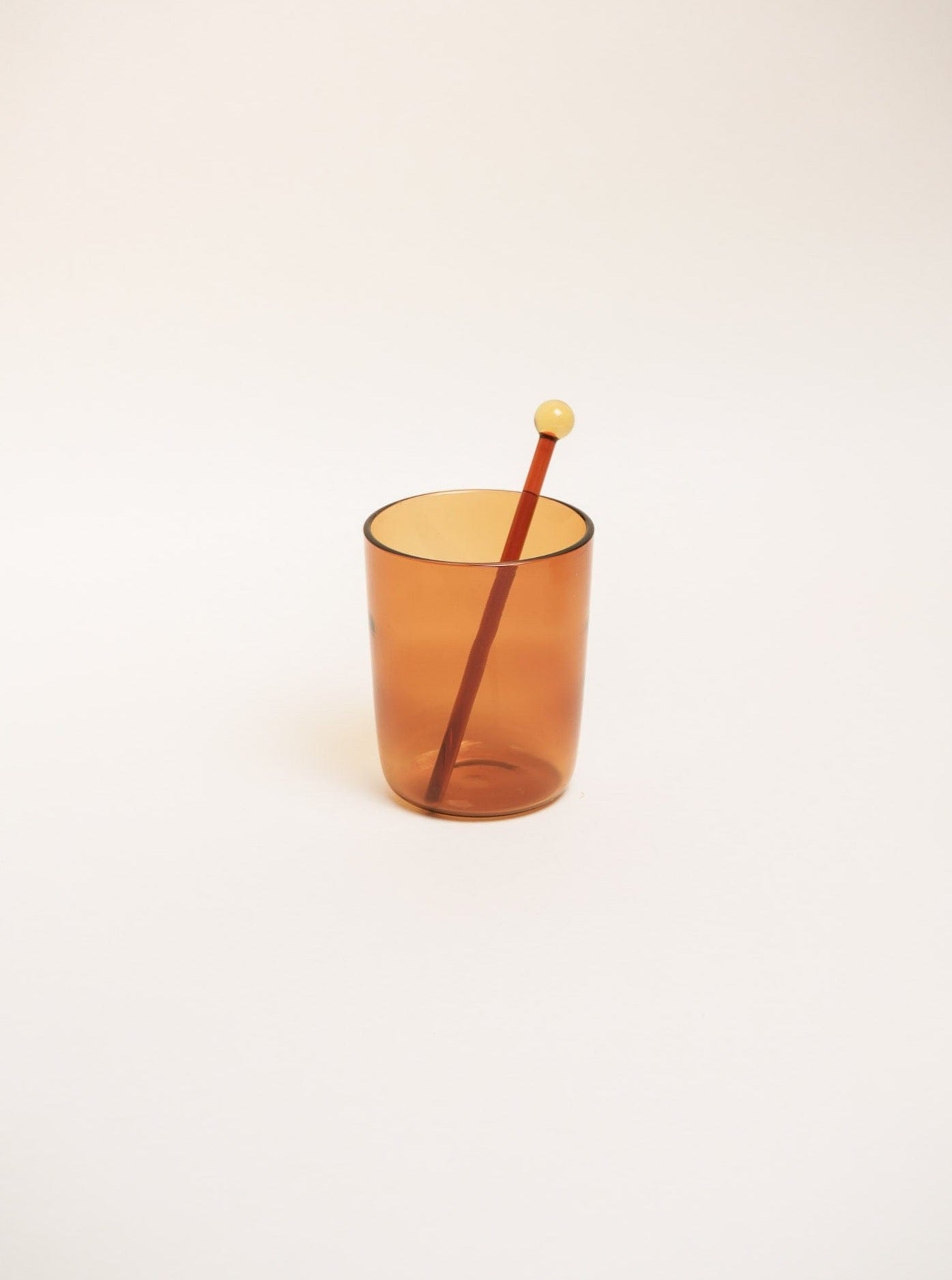 A brown glass cup with a wooden stick, perfect for Cocktail Stirrer Set stirring.