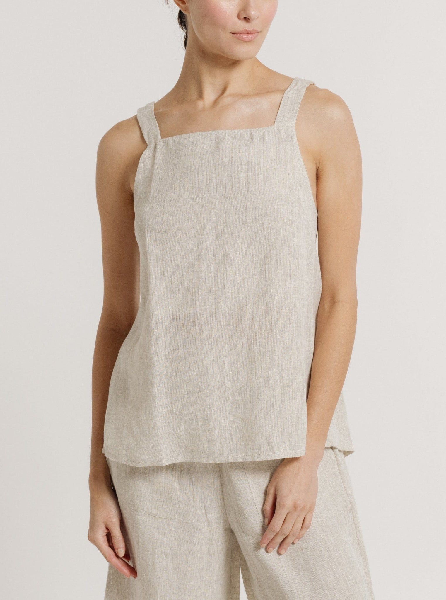 A woman sporting a Tie Back Linen Tank - Natural made of organic linen, ready for resort pre-orders.