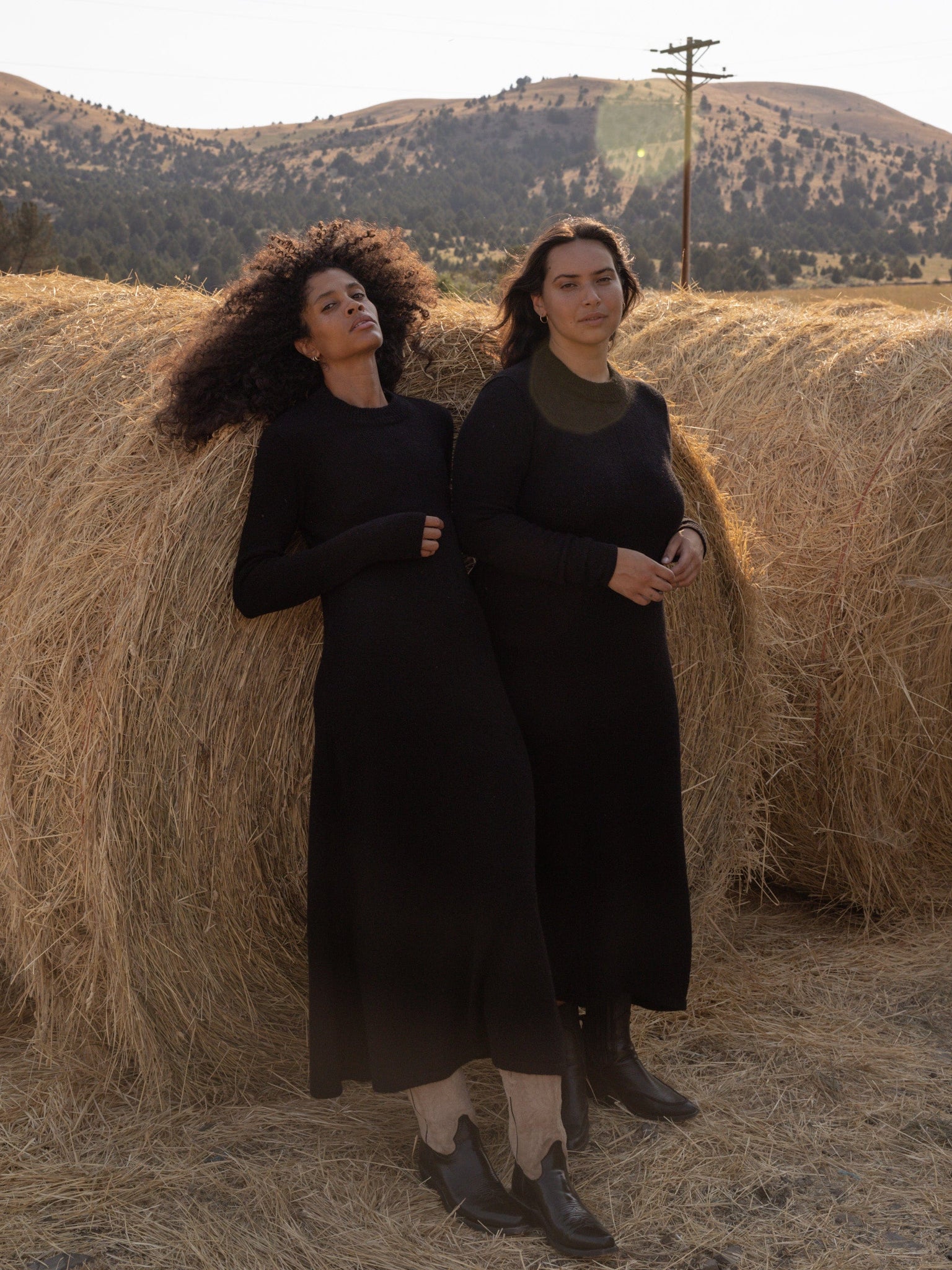 Two women in Ennis Dress - Black posing in front of a hay bale.