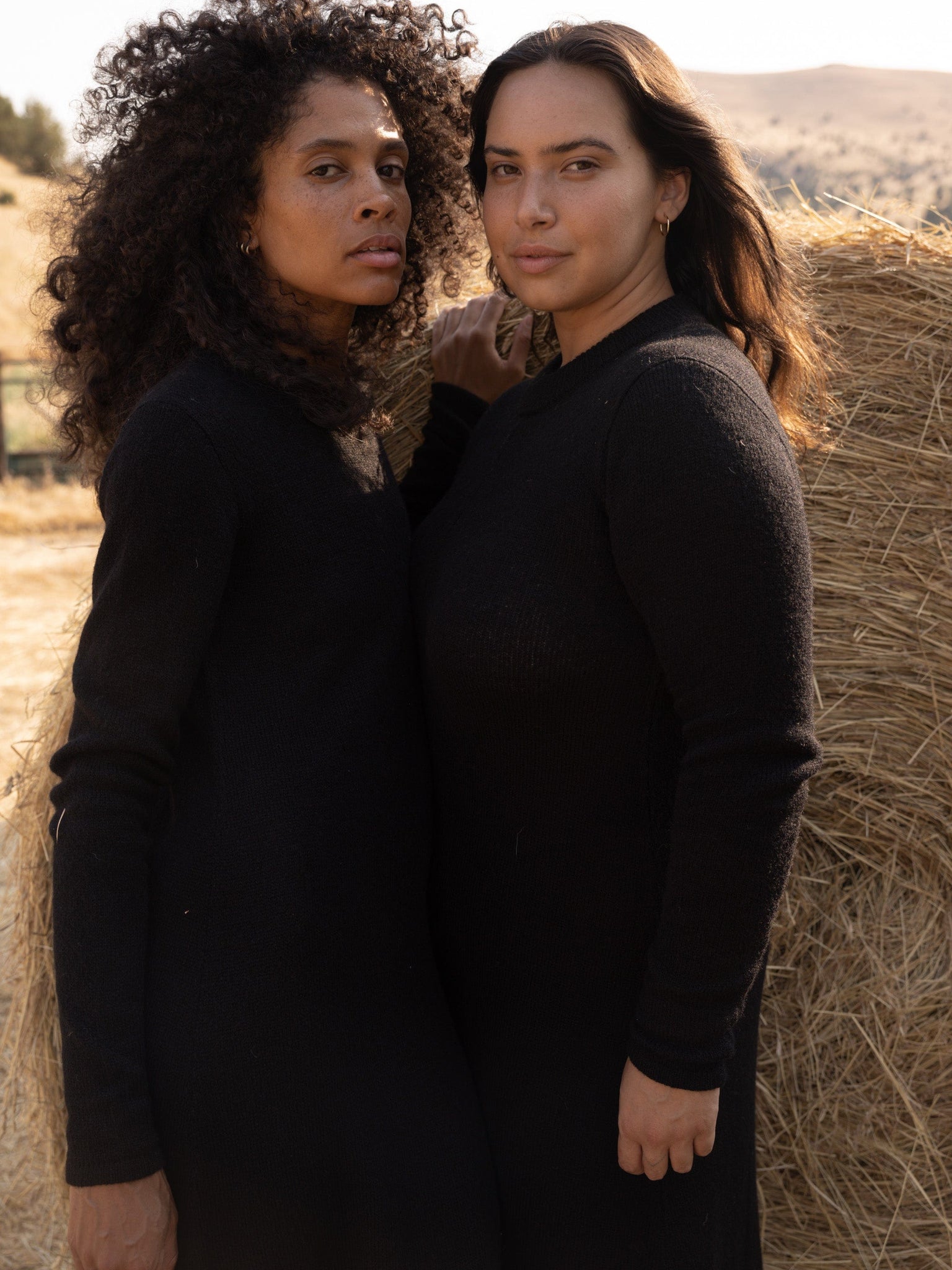 Two women standing next to an ethically-sourced Ennis Dress - Black.