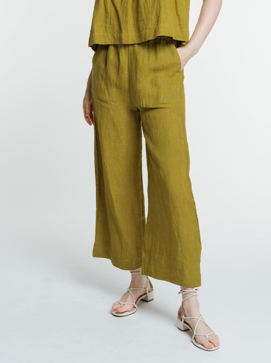 A woman wearing the Everyday Crop - Dried Tobacco jumpsuit and sandals.