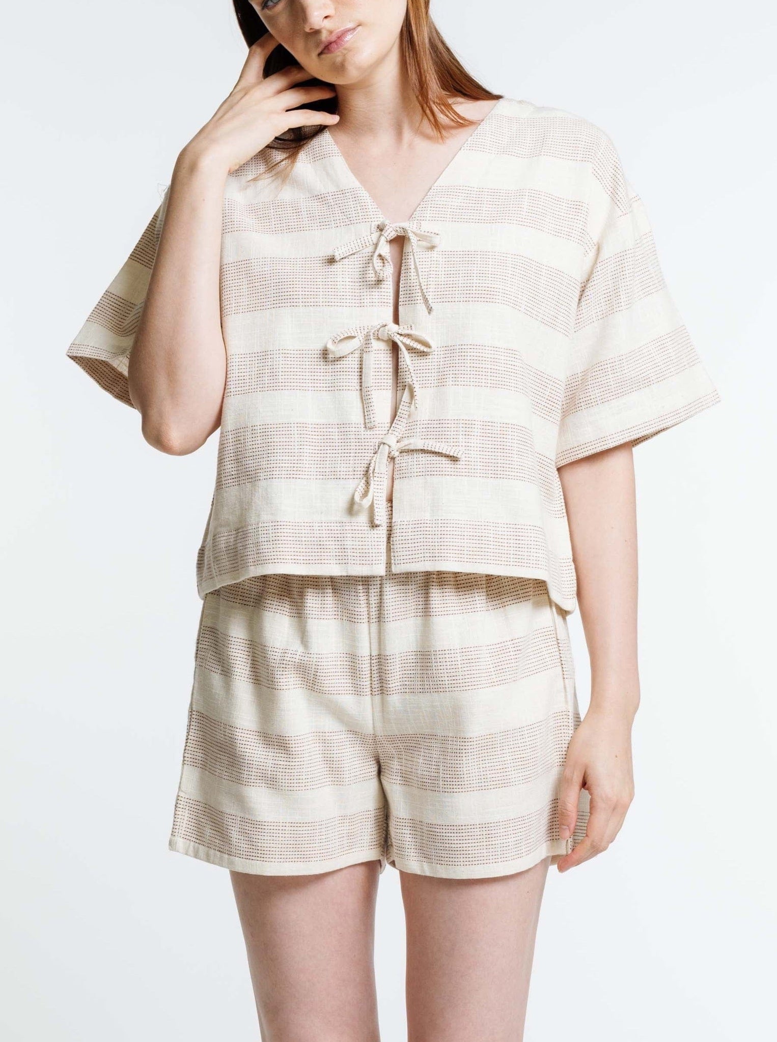 The model is wearing Everyday Shorts - Terracotta Ticking Stripe and a striped top.