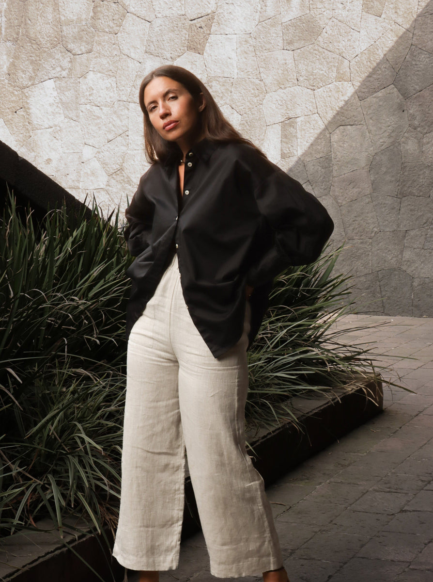 A woman wearing a Museo Button Up - Black shirt and white pants.