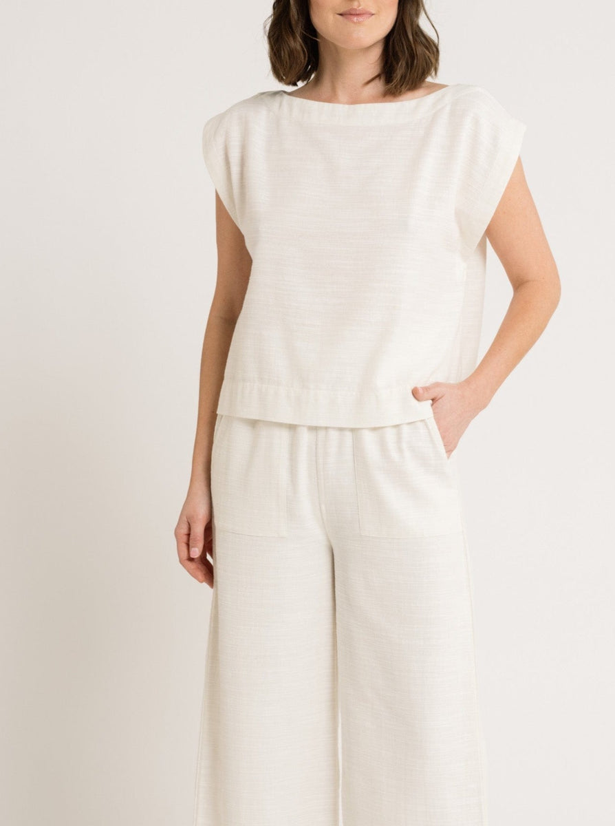 A woman wearing boxy white linen pants and the Everyday Top - Ivory with a wide neckline.