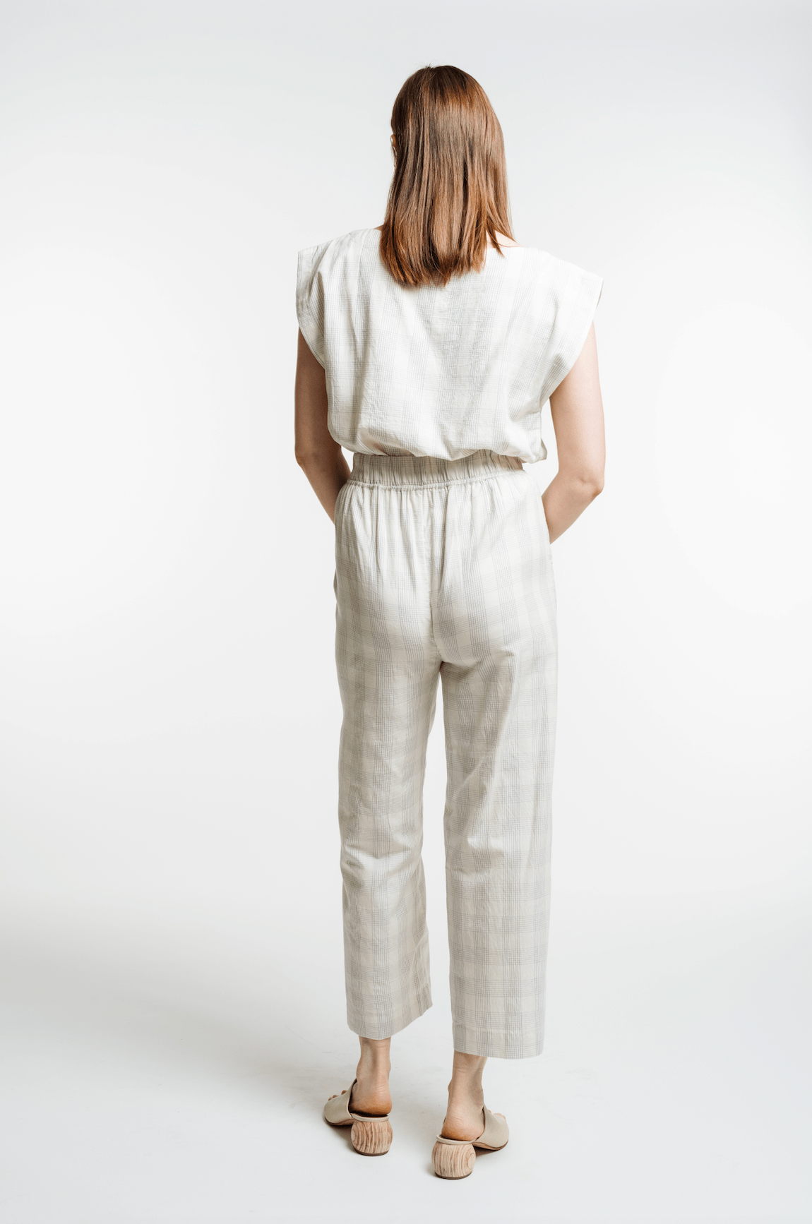The back view of a woman wearing the Everyday Crop Pant - Rivera Plaid jumpsuit.