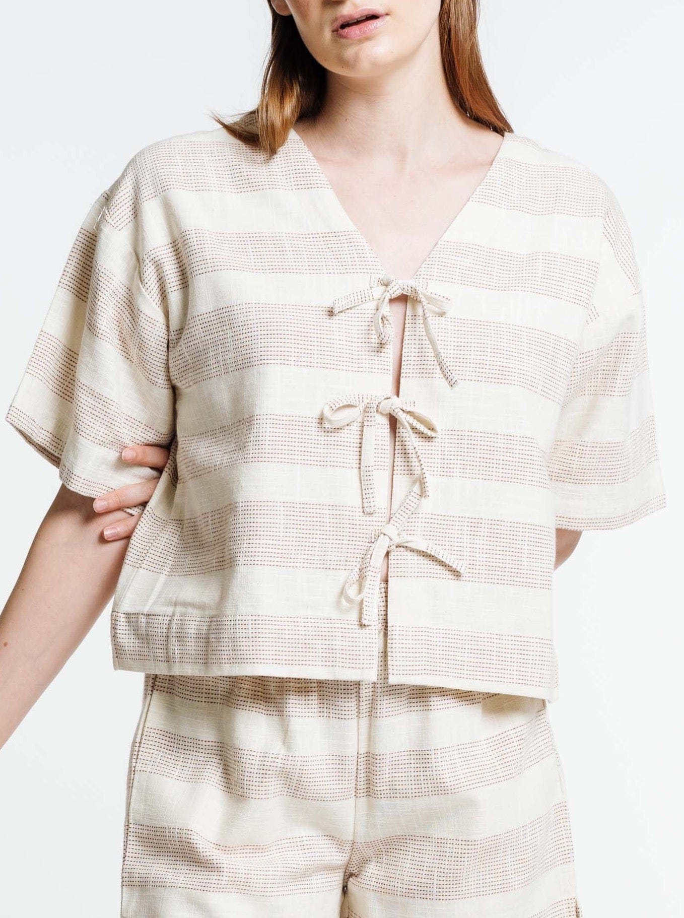 The model is wearing a Baker Top - Terracotta Ticking Stripe and shorts.