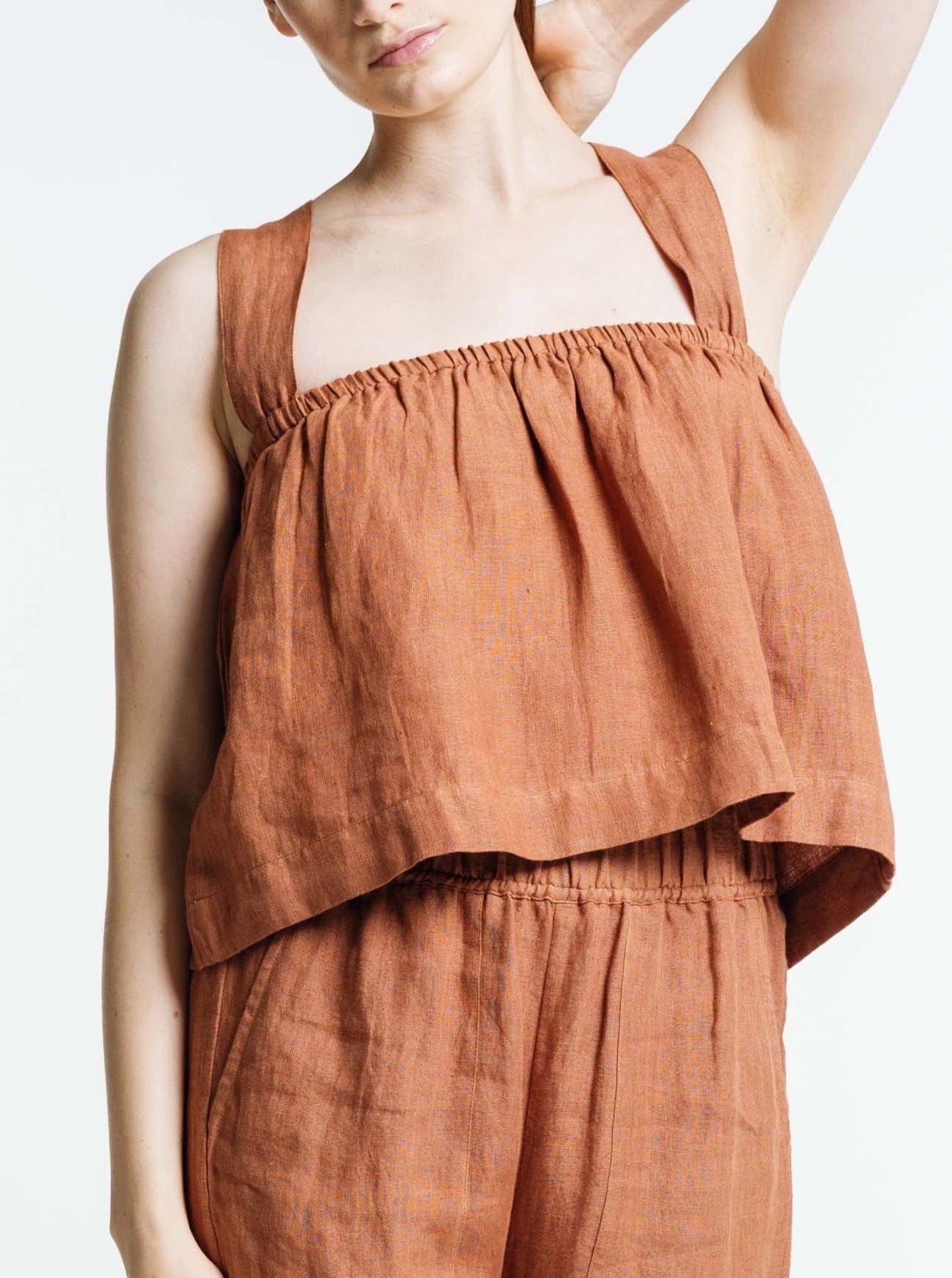 The model is wearing a Breeze Tank - Amber Brown linen top and shorts made from organic linen.