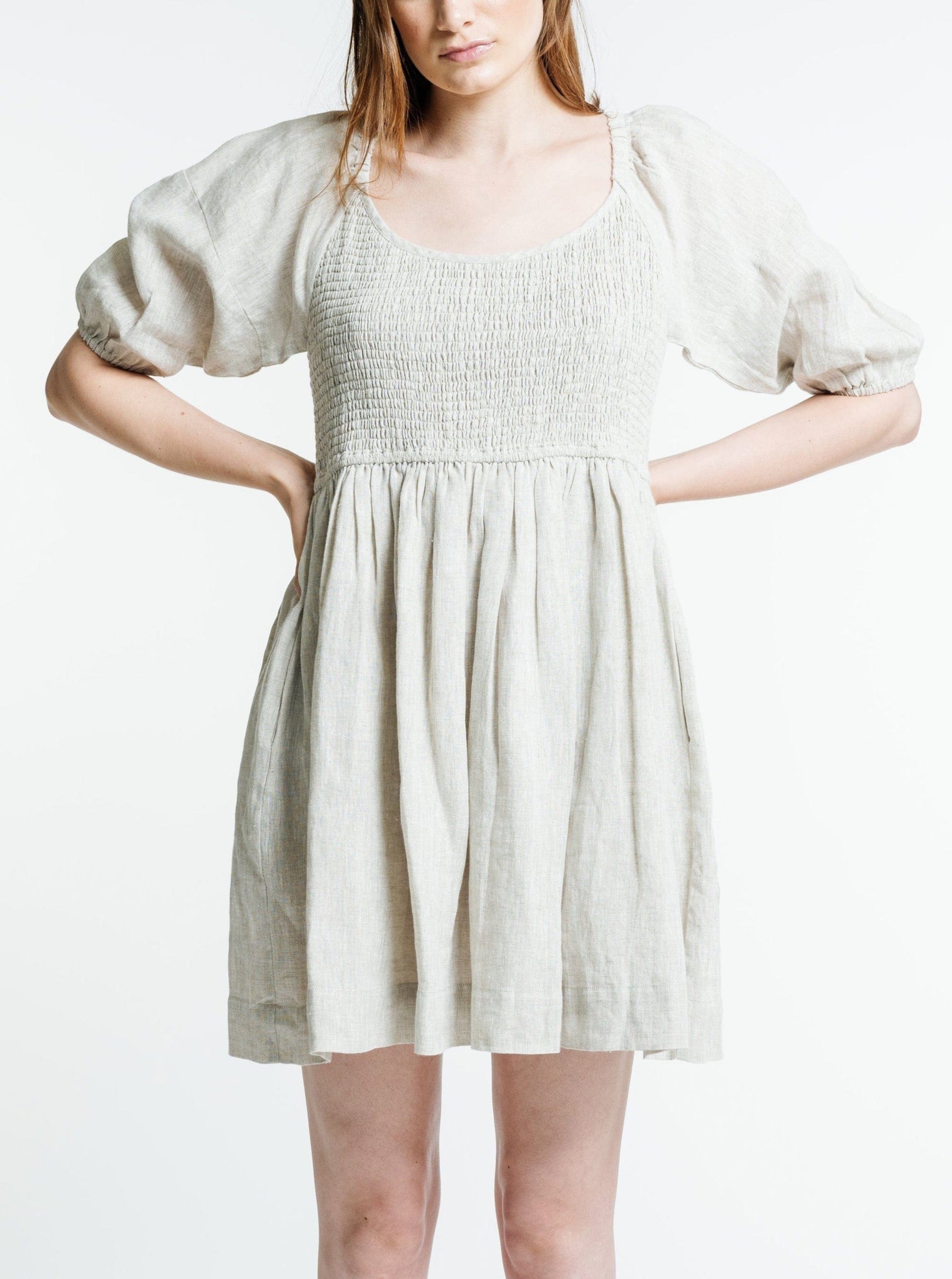 The model is wearing a Carmen Mini Dress - Natural in organic linen, perfect for the summer sun.