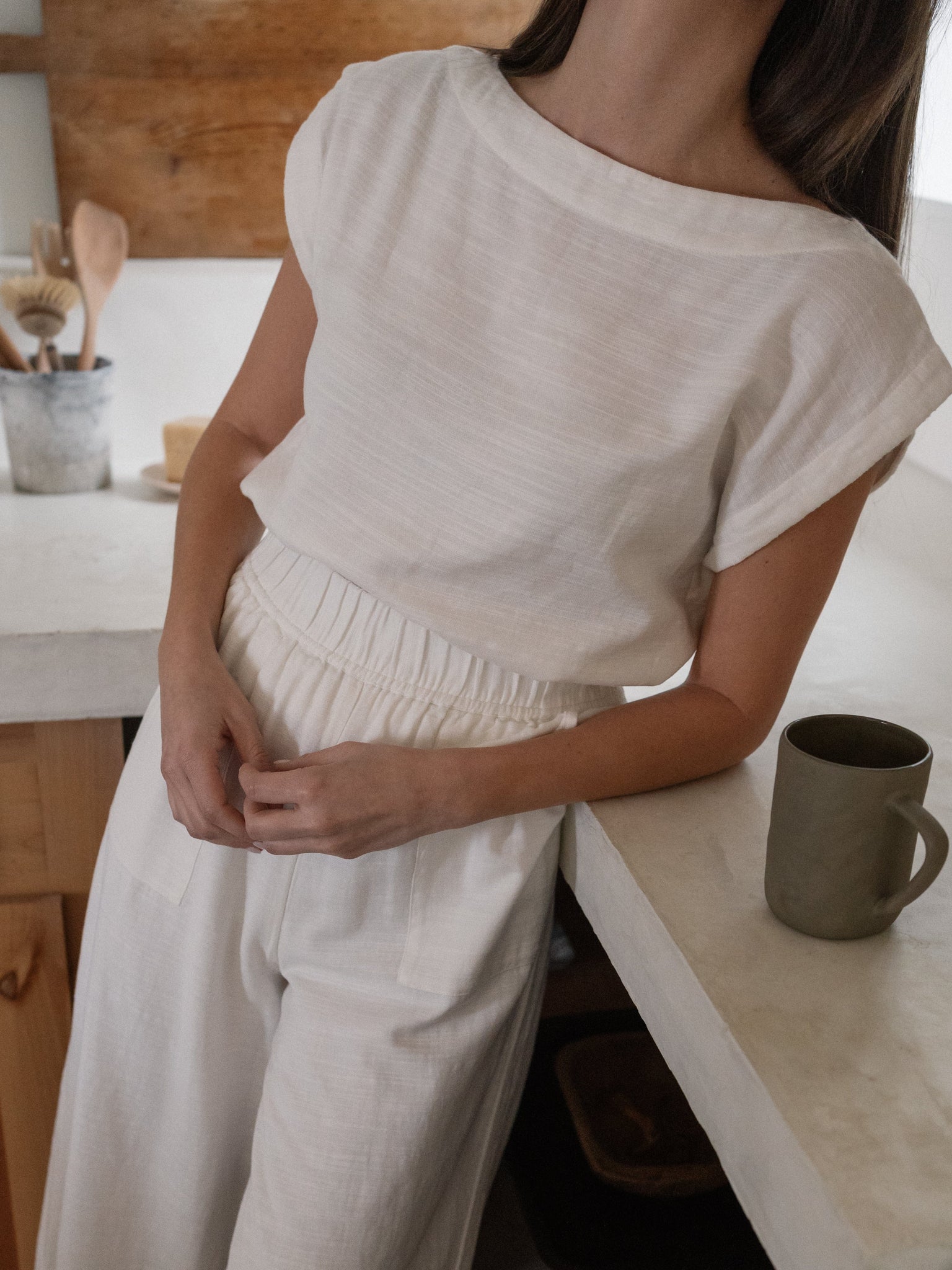 A woman in an Everyday Top - Ivory leaning on a kitchen counter.