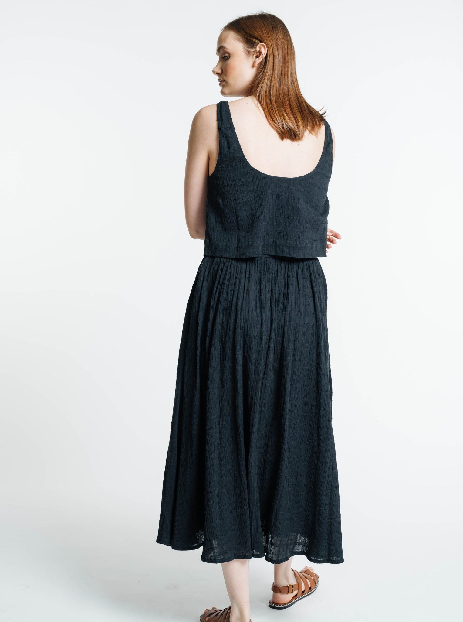 The back view of a woman wearing a Market Tank - Ink Plaid linen dress.